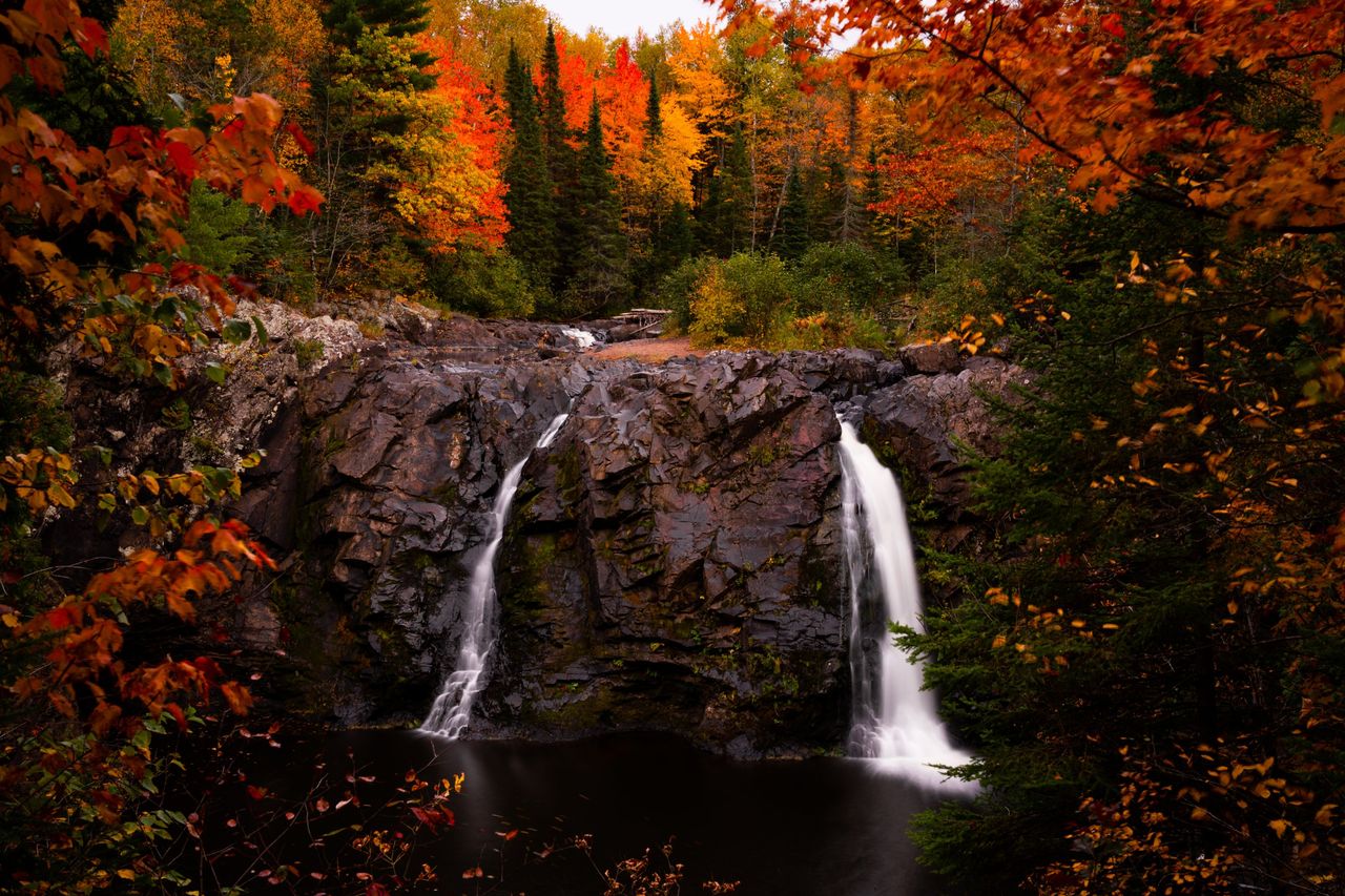 A pair of waterfalls framed by fall foliage