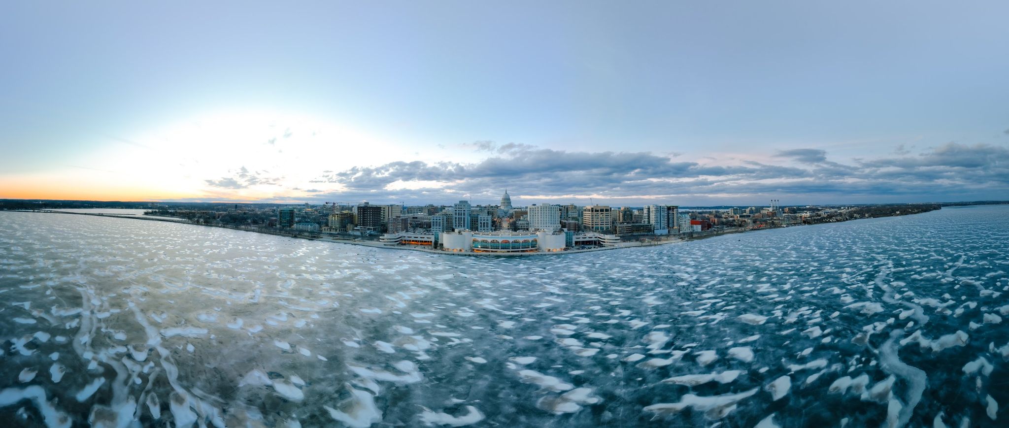 A snowy and frozen Lake Monona with the Monona Terrace and Madison Capitol in the background