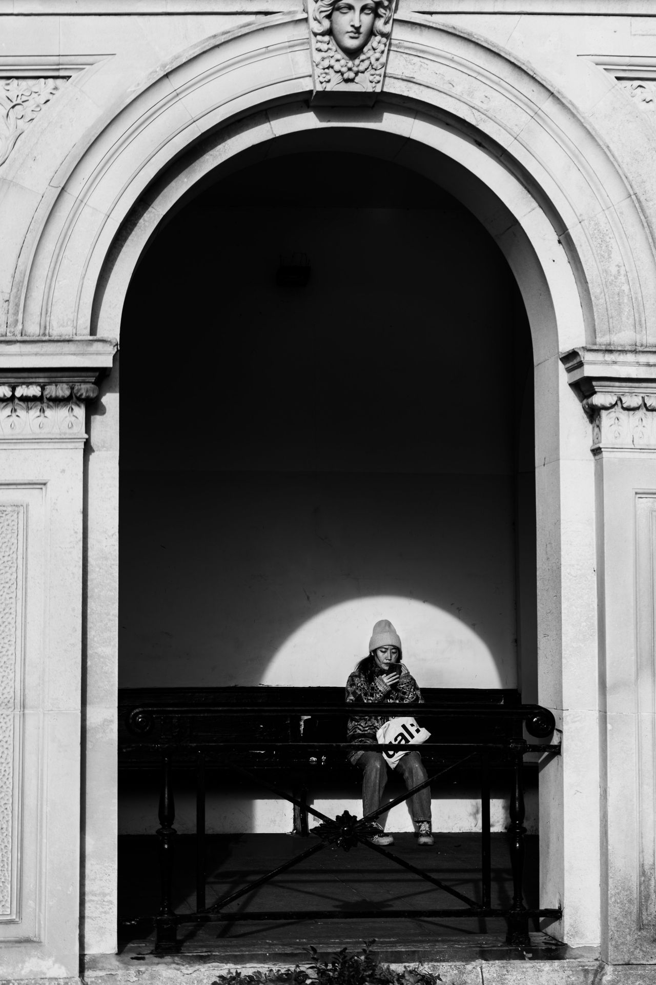Person looking at their phone on a bench spotlighted by sunlight
